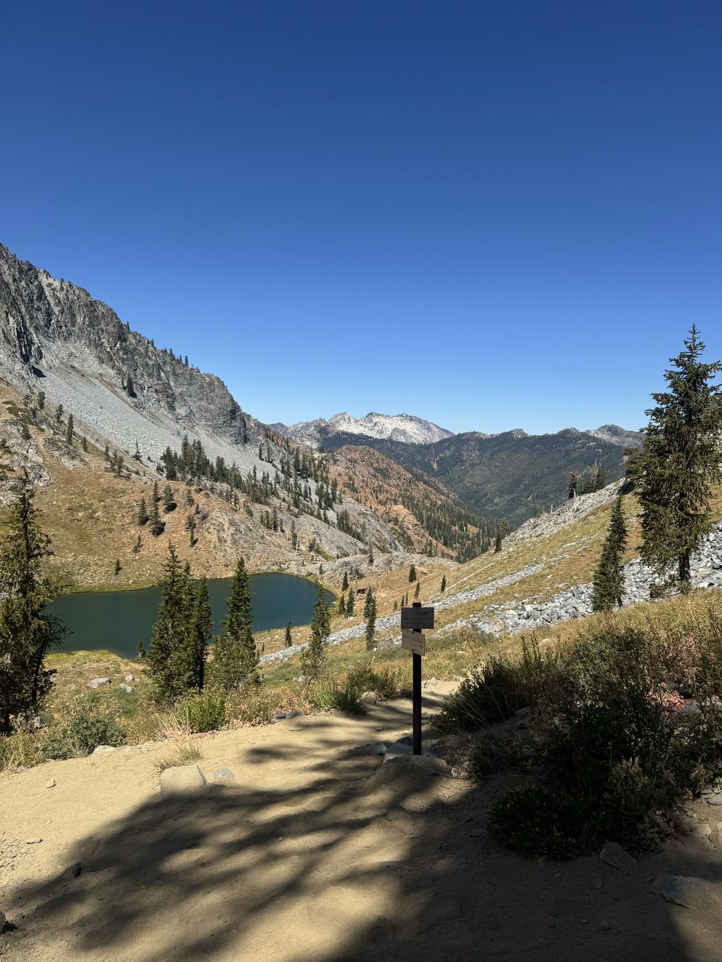 A trail sign on a pass above one of the lakes, granite ridges beyond.
